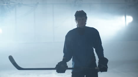 toma de retrato de un jugador de hockey masculino concentrado parado en la arena de hielo, sosteniendo un palo y mirando la cámara