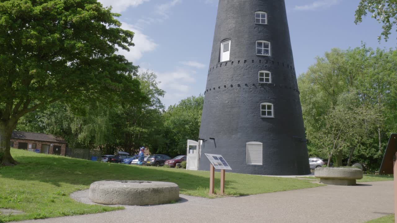 Historic windmill with millstones and info signs in a green park setting, Hessle