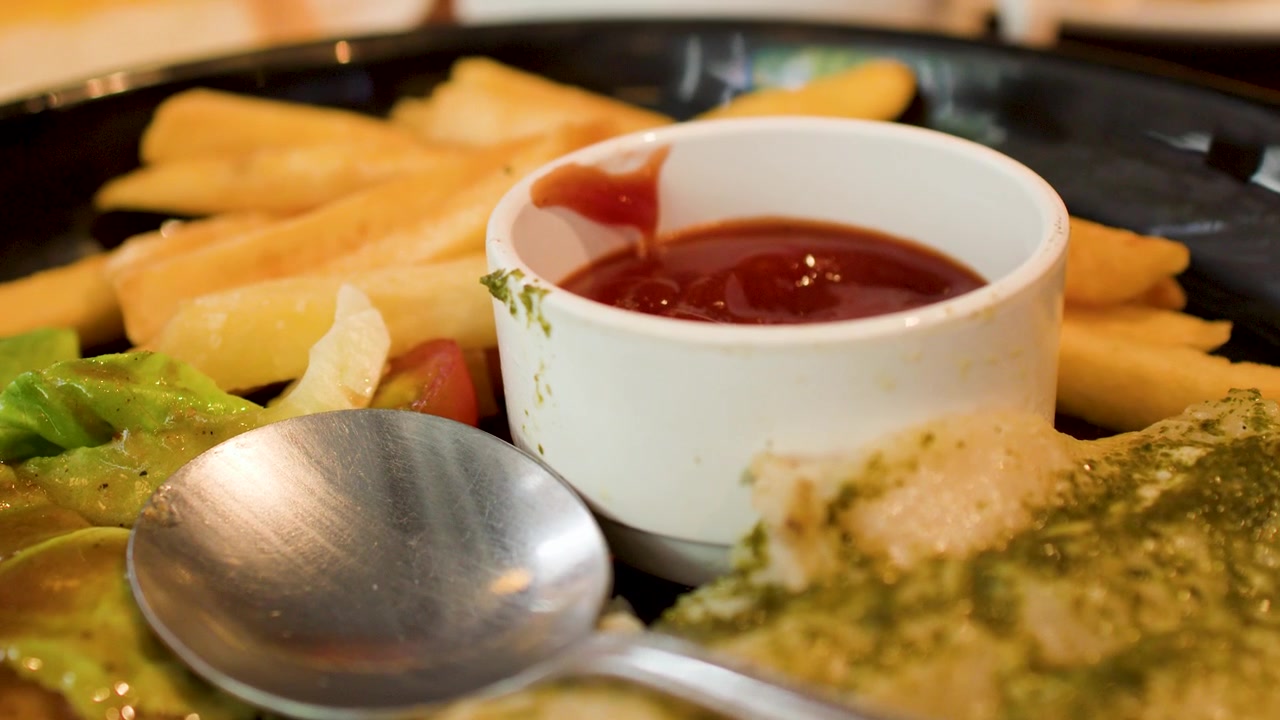 Una lenta panoramica della telecamera su un pasto da ristorante che include patatine fritte, insalata e salsa d'accompagnamento