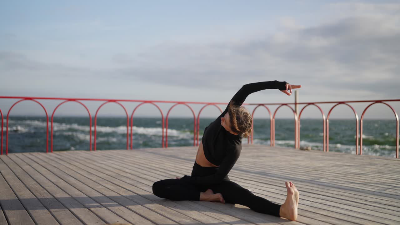 Woman doing yoga stretches on a pier overlooking the sea