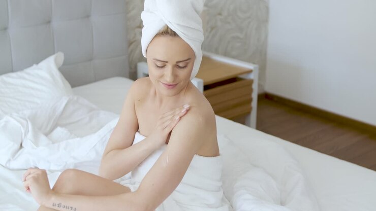 wanita paruh baya berambut pirang yang cantik melembabkan kaki setelah mandi