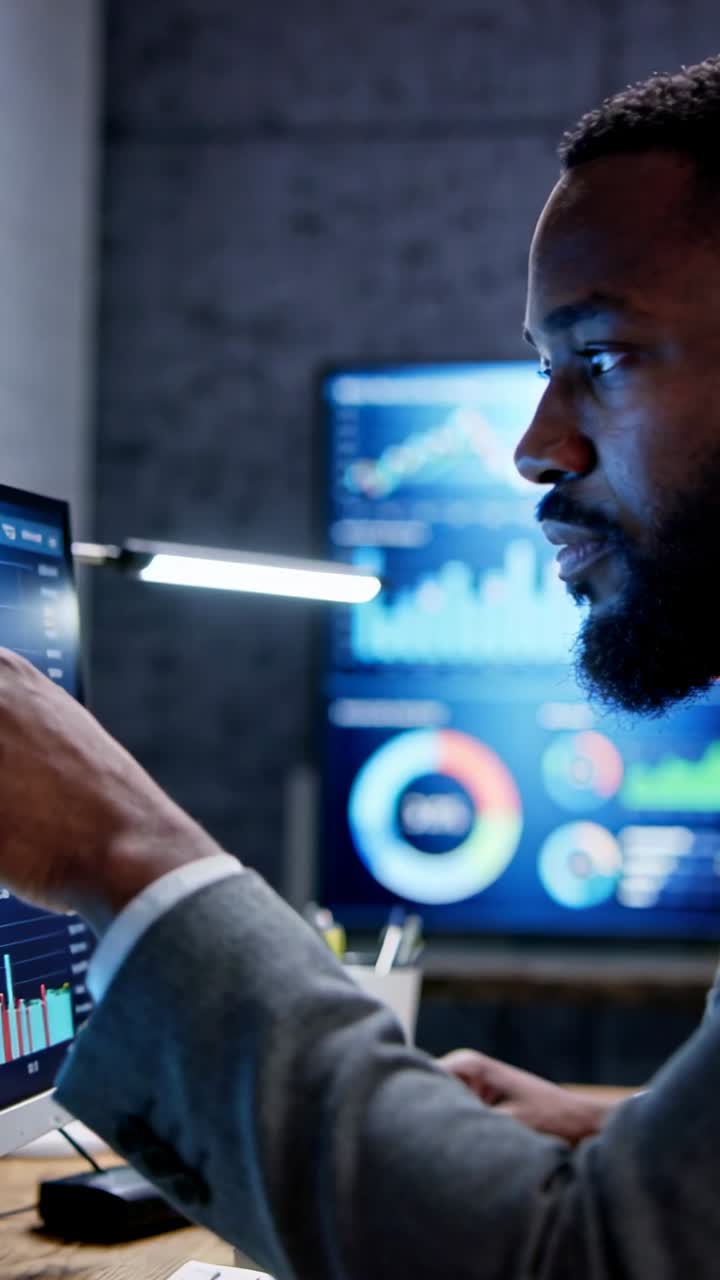 Vertical video: Pointing, analyst in suit analyzing charts at office with main monitor, copy space