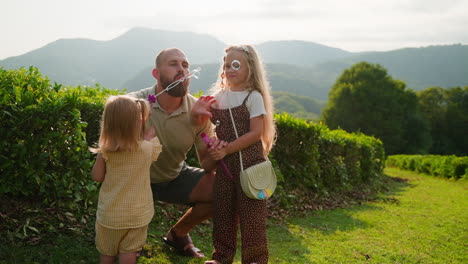 father and daughters playing with bubbles in nature