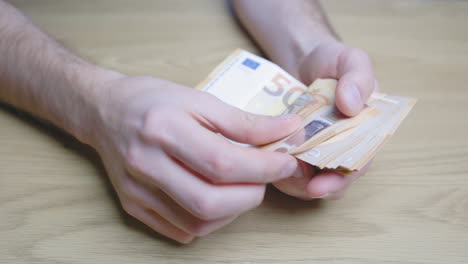 contando 50 euros, billetes de papel moneda y dejando algunos en una mesa de madera