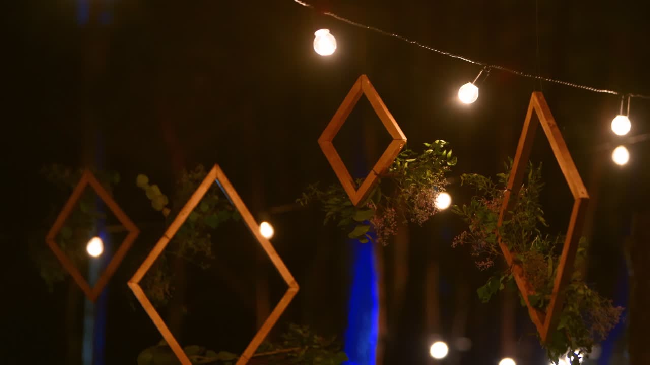 marcos de madera con composiciones florales arreglo colgado en boho estilo lugar de la fiesta de bodas al aire libre en el bosque de pinos con luces de cuerda o luces de hadas por la noche. país o decoración orgánica rústica
