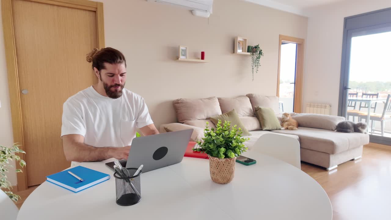 Man working on laptop at home with cats