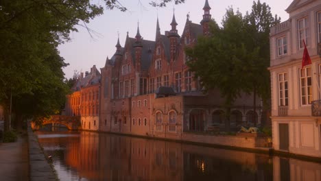 pan lento, que muestra los edificios antiguos junto a los canales en bruges, bélgica después de la hora dorada con iluminación escénica