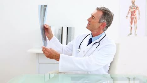 médico maduro examinando en rayos x en su escritorio