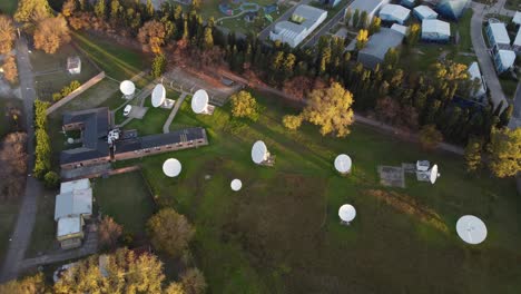 aerial view of satellite dishes in green field at sunset