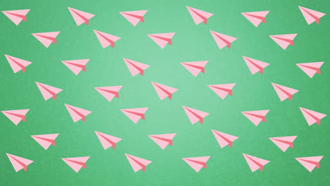 digital animation of multiple pink paper planes icons floating against green background