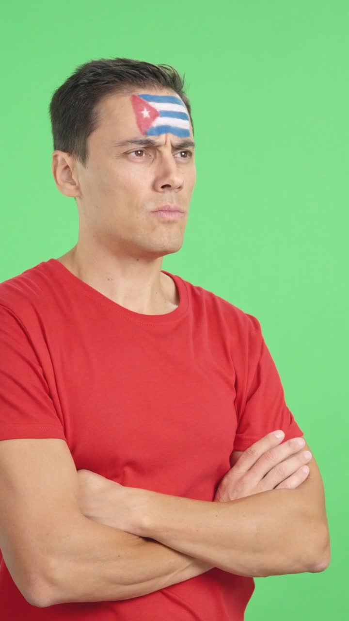 Man with cuban flag painted looking away with serious expression
