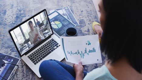 African-american-woman-holding-a-document-having-a-video-call-on-laptop-at-home