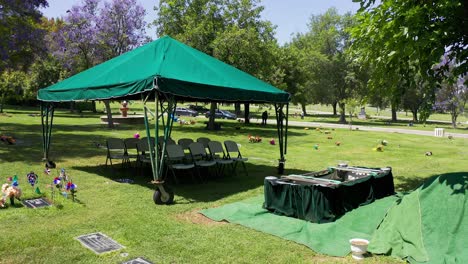 slow dolly aerial shot of a burial site ready for interment as the funeral party arrives in the background at a california mortuary