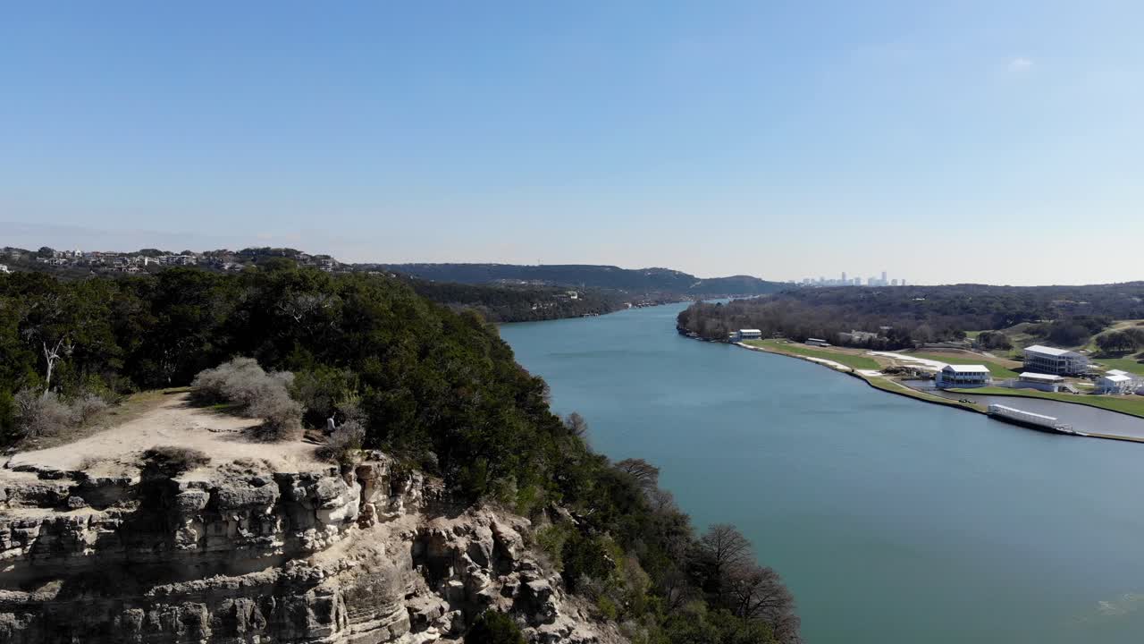 Aerial Austin Pennybacker Bridge - flying low off the ledge towards the other side of the overlook. Panning right to reveal the river and the Austin skyline in the far distance.