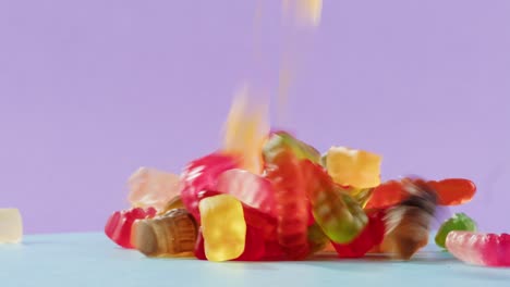 colorful gummy candies on a light blue surface against a purple background