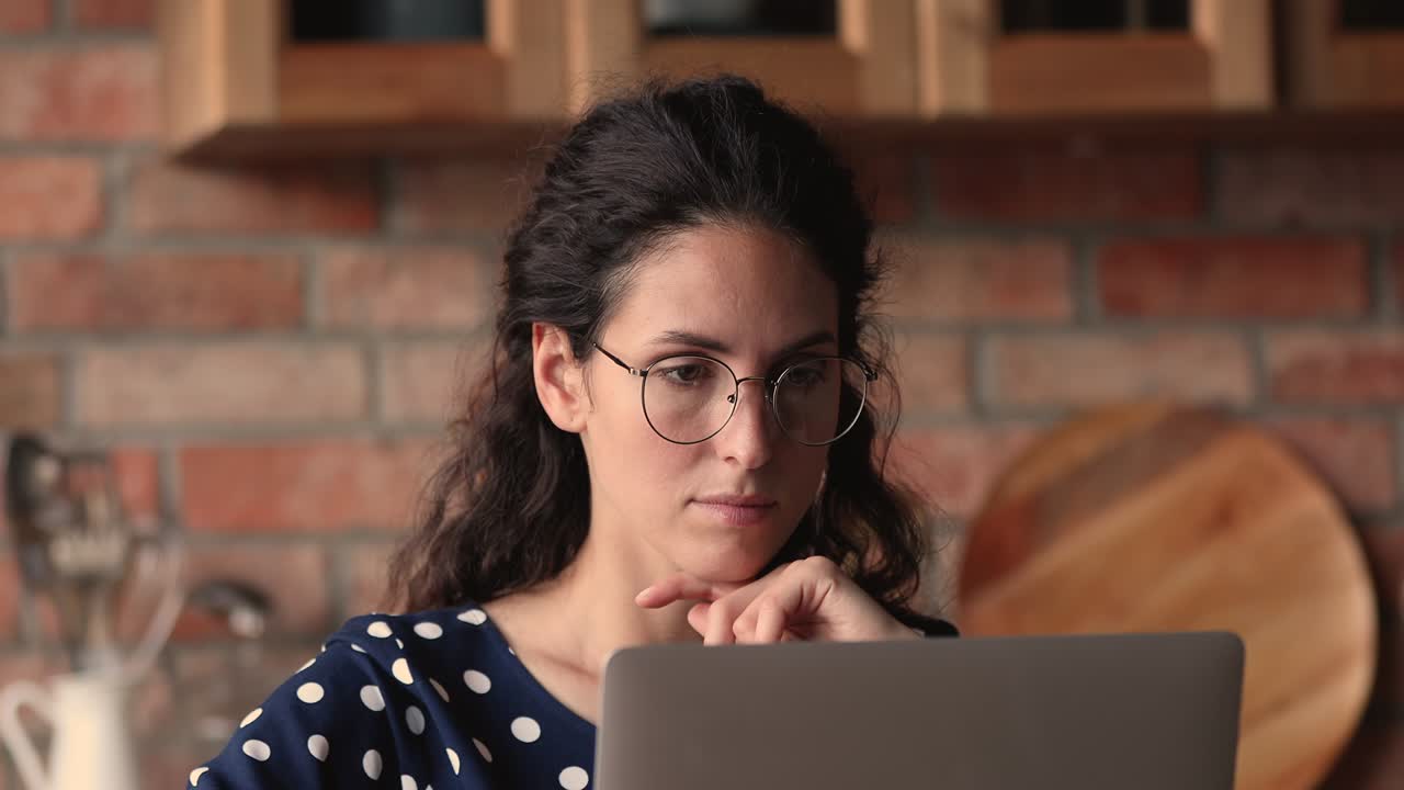 una joven latina bonita con gafas trabajando en la computadora.