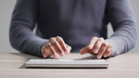 Video-of-midsection-of-biracial-businessman-at-desk-typing-on-computer-keyboard