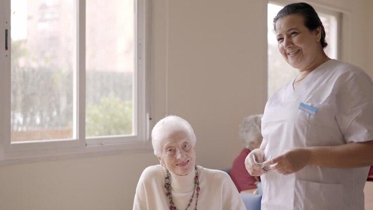 Caregiver smiling at camera next to old people in geriatric