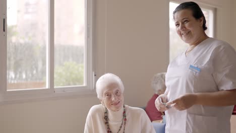 caregiver smiling at camera next to old people in geriatric