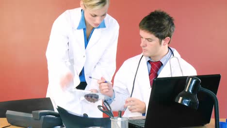 Male-and-female-doctors-signing-documents-in-office