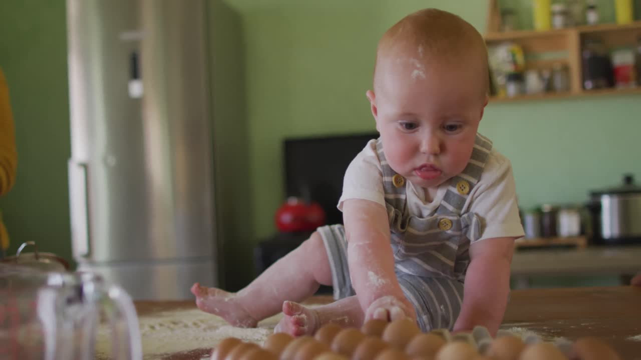 Happy caucasian baby sitting on countertop in kitchen