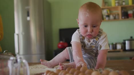 happy caucasian baby sitting on countertop in kitchen