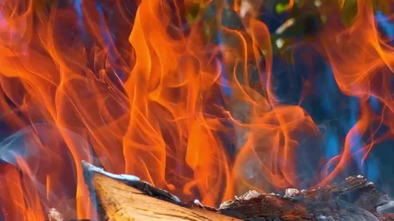 Chamas de fogo queimando um tronco de madeira texturizado em close-up. Fogueira brilhante ardendo em um pedaço de madeira com fumaça contra um fundo escuro suave
