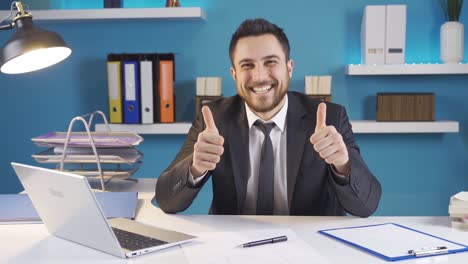 hombre de negocios mirando a la cámara y sonriendo mientras trabaja en la computadora portátil.