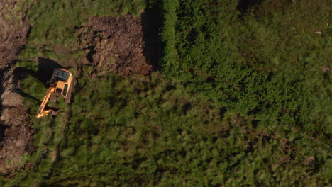 Top-down-aerial-shot-from-green-scrubland-to-excavation-site