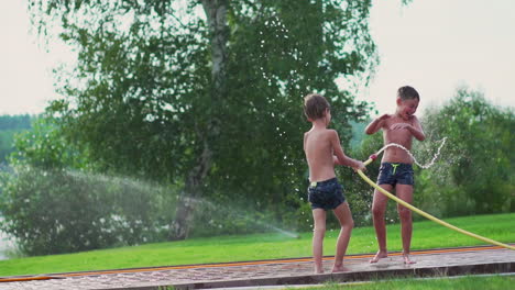 children play in summer with water pouring from a hose