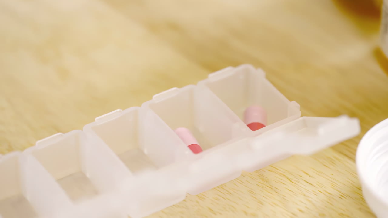 Un professionista sanitario, medico o farmacista, prepara un dispensatore di farmaci per i pazienti. Un portapillole medico con dosi di compresse per l'assunzione quotidiana di medicine, con farmaci vitaminici colorati e capsule.
