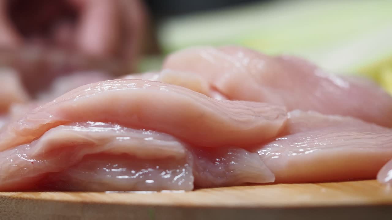 Pollo crudo a fette su tagliere di legno.
