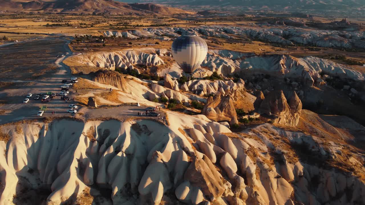 globo pasando por el acantilado en el valle del amor capadocia en turquía con la gente mirando desde el borde de la colina al amanecer en goreme