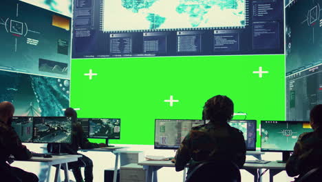 Team-of-IT-military-specialists-working-with-a-greenscreen-on-a-big-display