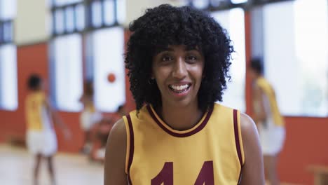 Retrato-De-Una-Jugadora-De-Baloncesto-Afroamericana-Sosteniendo-Una-Pelota-En-Una-Cancha-Cubierta,-En-Cámara-Lenta