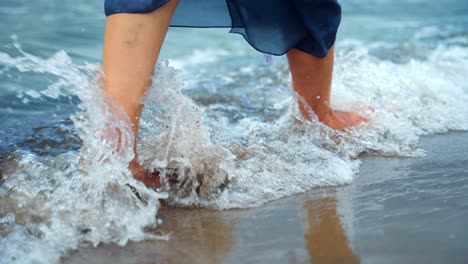 cerca de pies de mujer caminando descalzo en la playa de arena en agua de mar