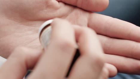 two big pink round shapes fall into palm of hand from pill bottle. close-up, top view