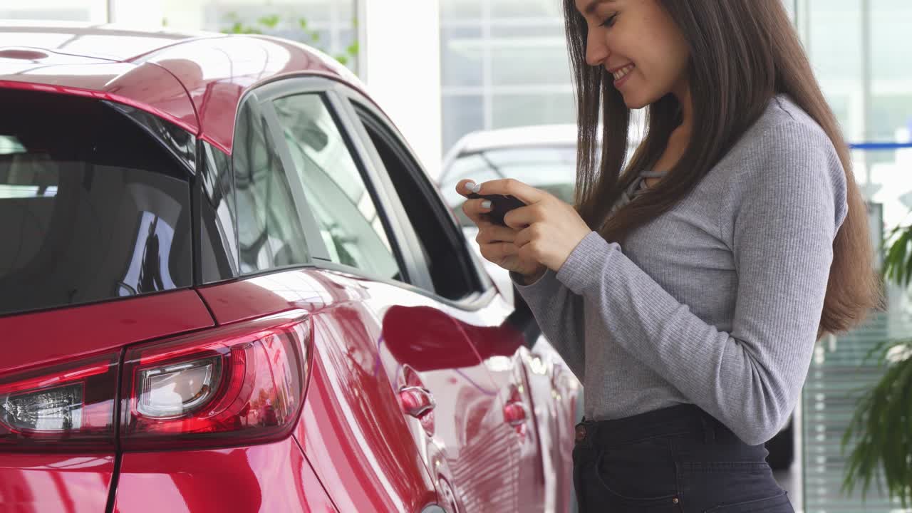 fotografía recortada de una mujer usando su teléfono inteligente de pie cerca de su coche