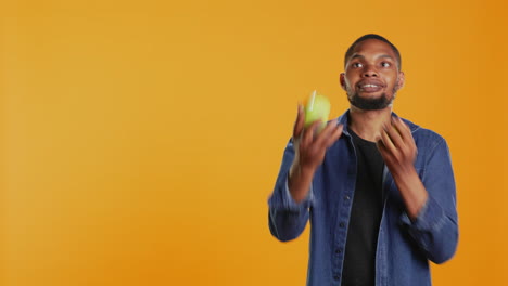 Playful-person-juggling-in-the-studio-with-ripe-green-apples