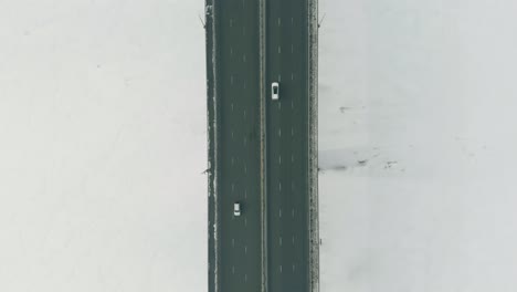 wide highway bridge with moving vehicles over frozen river