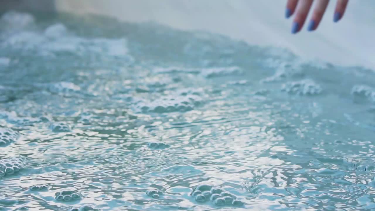 거품이 이는 자쿠지 물에 손을 담그는 소녀