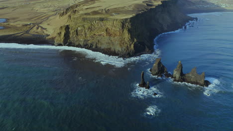 vista de pájaro de los acantilados y formaciones rocosas de reynisdrangar en la playa de arena negra de reynisfjara en el sur de islandia