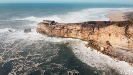 vista aérea de un océano rocoso con olas estrelladas en nazare, portugal