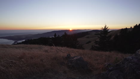 puesta de sol justo por encima del horizonte en el monte tamalpais con stinson beach y colinas ondulantes en el fondo