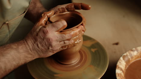 Artist-hands-sculpting-product-in-pottery.-Man-making-clay-product-in-workshop