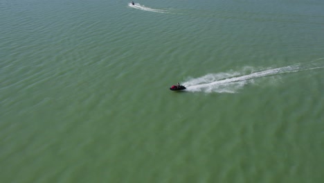 rider on fast, speedy jet ski sea doo on lake during sunny summer day - aerial