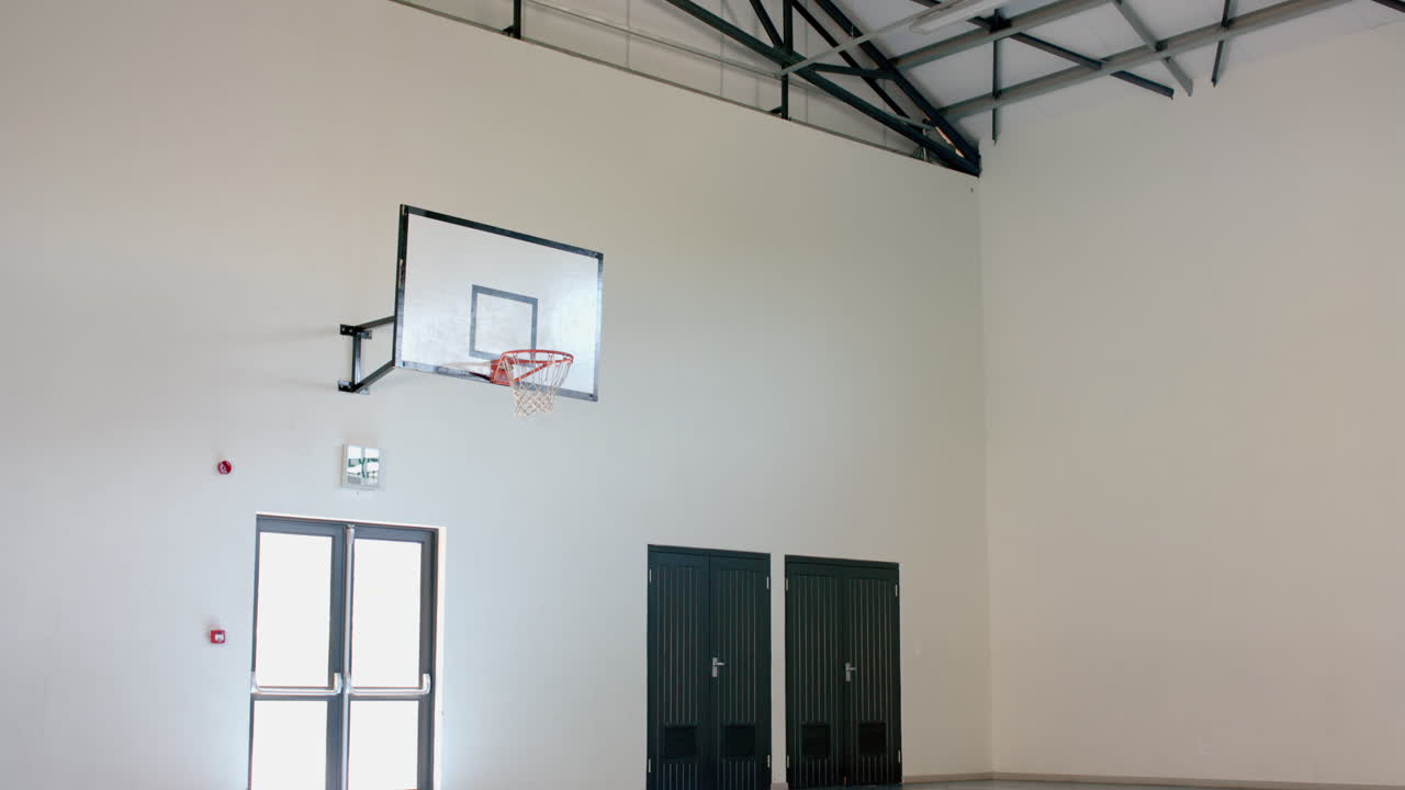 un aro de baloncesto interior está montado en una pared blanca en un gimnasio