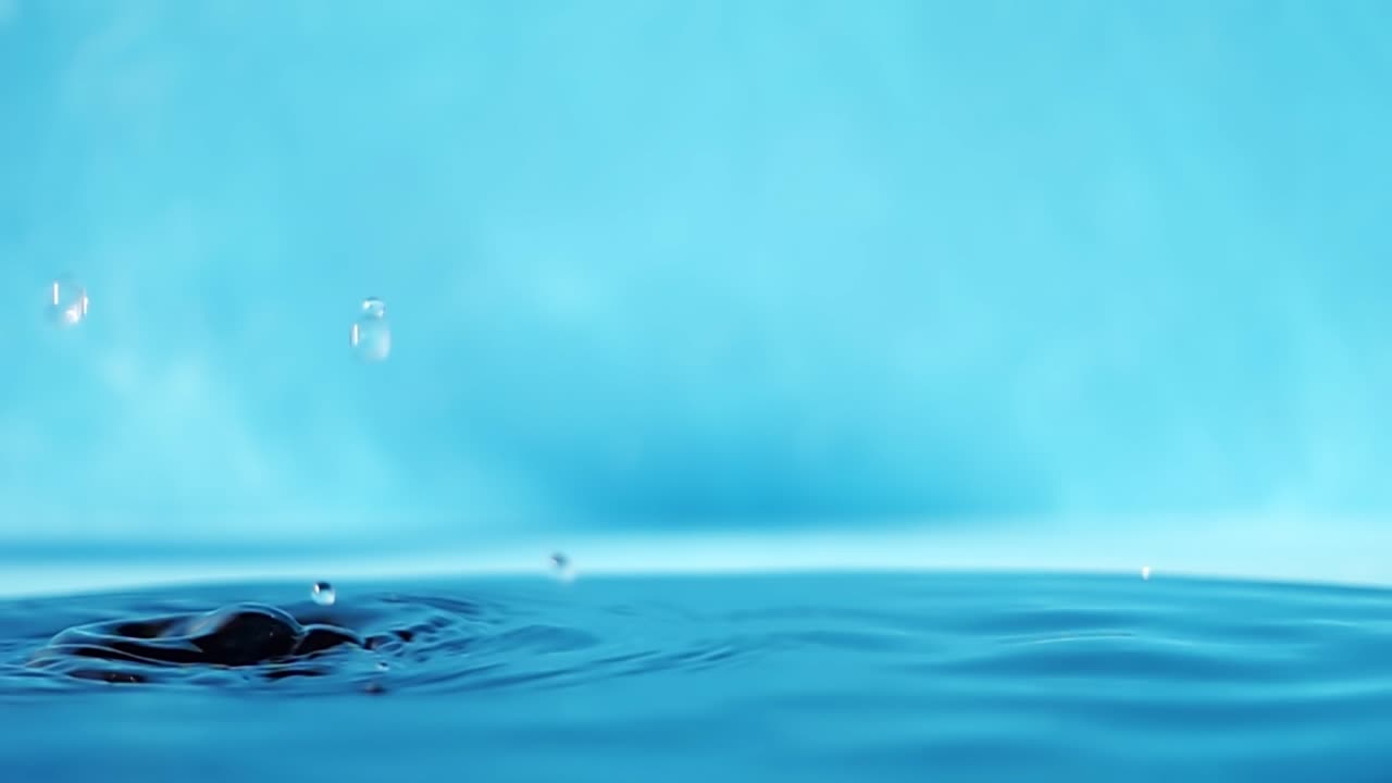 파란색 배경에 떨어지는 물방울과 함께 물 표면의 느린 모션 4k 비디오.