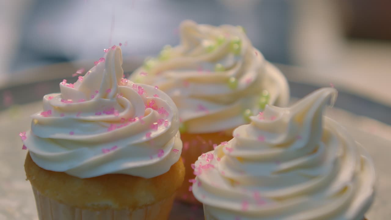 Una persona sparge zuccherini su tre cupcake