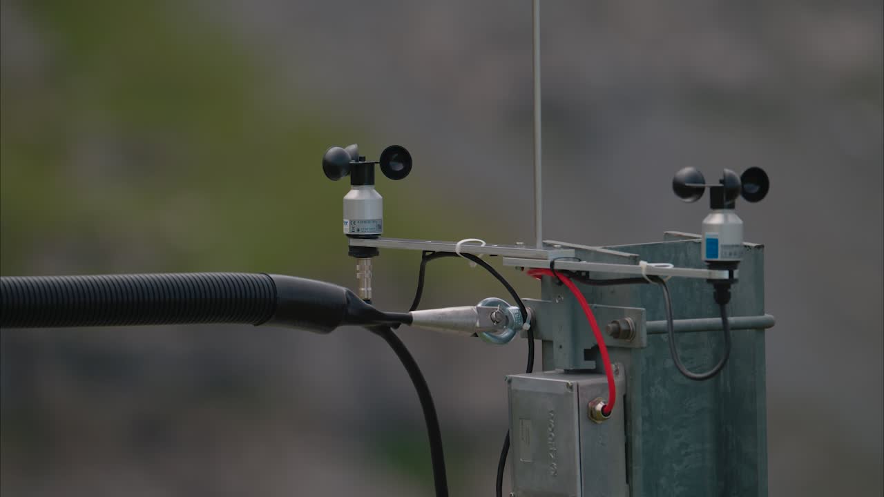 Close-up view of two anemometers mounted on a metal support above a mountain railway pillar